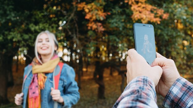 Herbstfreizeitpaar, das Zeit im Naturpark genießt und Bilder auf Smartphone nimmt