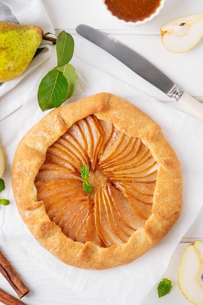 Herbstgalette mit Birnen, Walnüssen, Karamellsauce und Zimt auf weißem Holzgrund