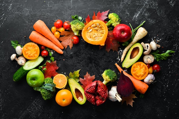 Herbstgemüse und Obst auf schwarzem Steinhintergrund Kürbis Tomaten Mais Granatapfel Kaki Apfel Ansicht von oben Freier Kopierraum