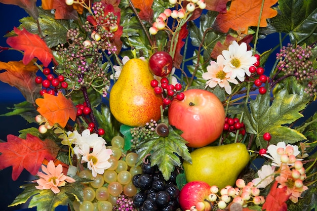 Herbsthintergrund der gelben Blätter, Äpfel, Birnen und Trauben Herbststillleben