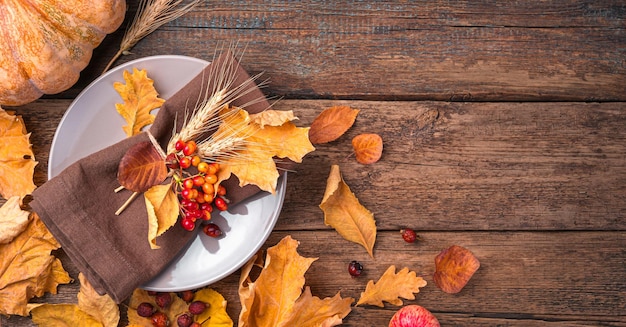 Herbsthintergrund mit Besteck und Herbstblättern auf einem hölzernen Hintergrund