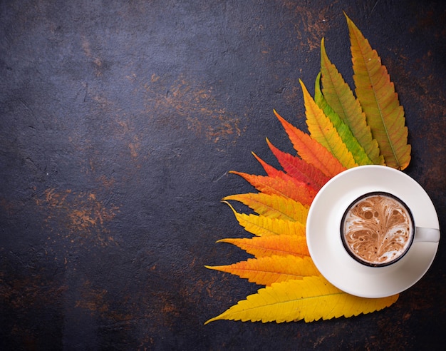 Herbsthintergrund mit Blättern und Tasse Kaffee.