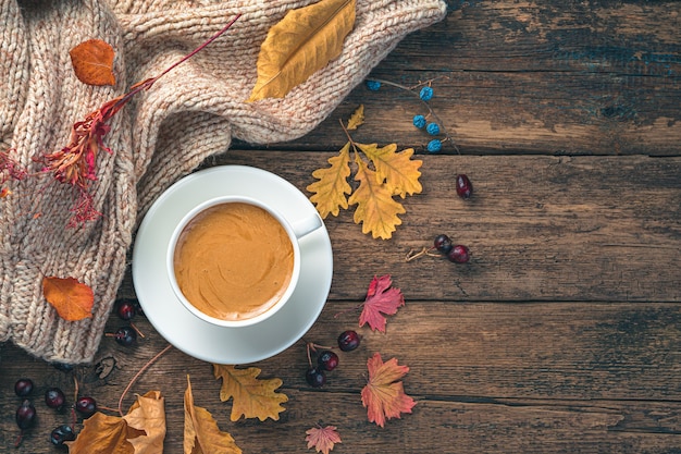 Herbsthintergrund mit einer tasse kaffee und trockenen blättern auf einem holztisch getönten bild