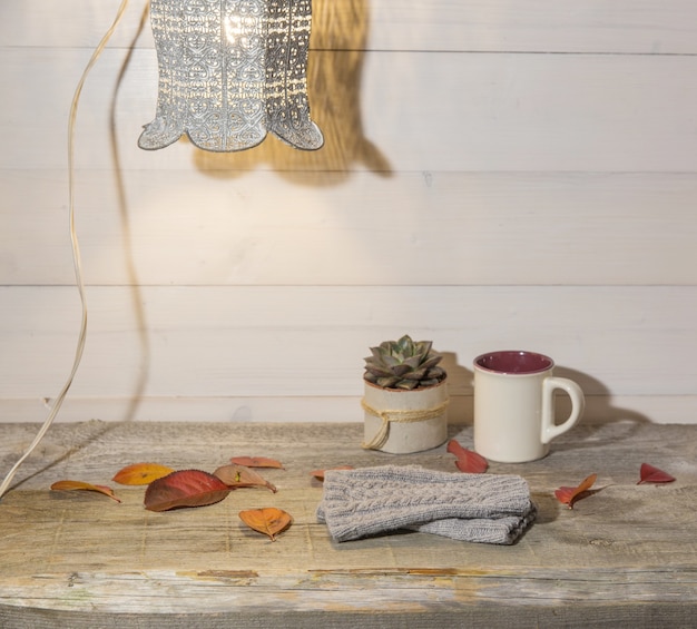 Herbsthintergrund, Wollhandschuhe, bunte Blätter, saftig, Tasse Kaffee auf einem Vintage-Holztisch und Retro-Lampe.