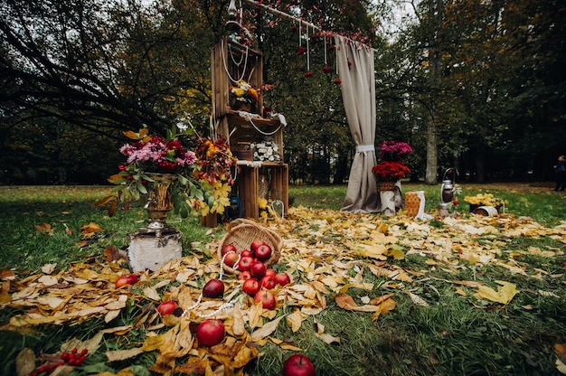 Herbsthochzeitszeremonie auf der straße auf dem grünen rasen. dekor mit bögen der frischen blumen für die zeremonie.