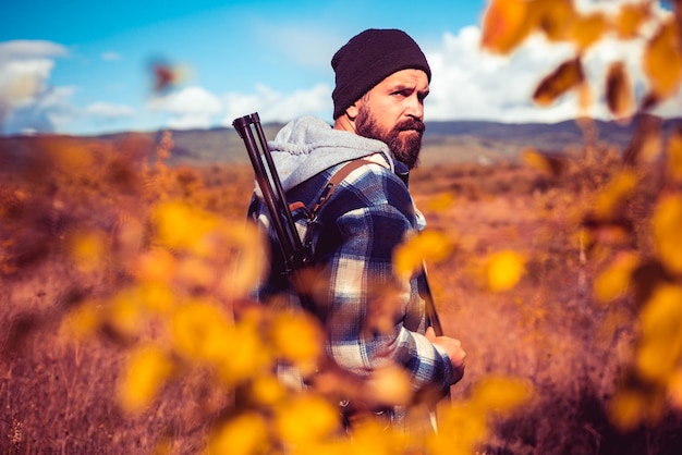 Herbstjagdsaison Jäger mit Schrotflinte auf der Jagd Herbstjagd Wilderer mit Gewehr, der som...