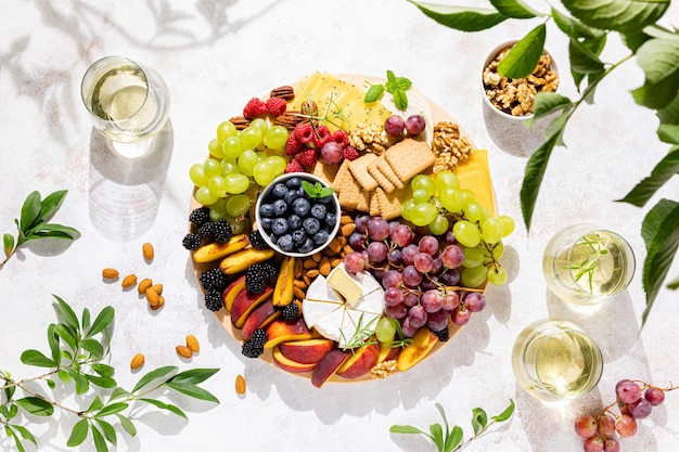 Herbstkäseplatte mit frischen Früchten und Beeren, serviert mit Weißwein-Draufsicht