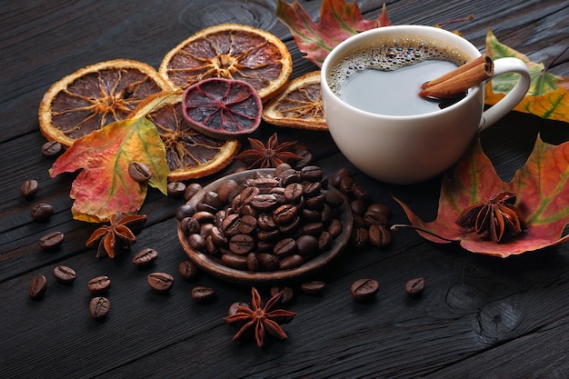 Herbstkaffee Kaffee in einer weißen Tasse getrockneten Zitrusfrüchten und Gewürzen auf einem Holztisch trocknen bunte Ahornblätter und eine Tasse Kaffee Herbststimmung