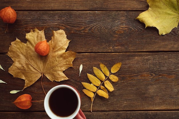 Herbstkaffee oder Tee warme Blätter Holzoberflächenwandkonzept. Saisonale Gemütlichkeit. Krankheitsprävention