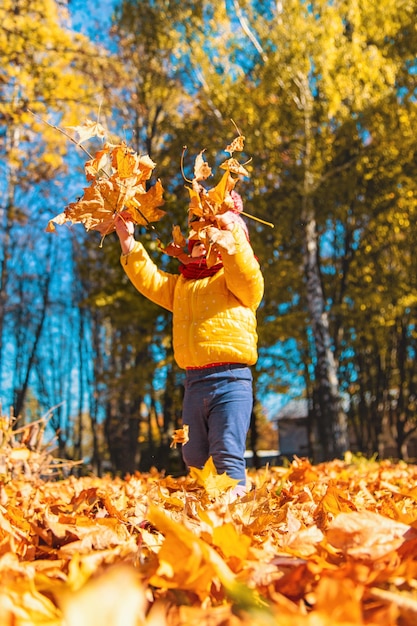 Foto herbstkind im park mit gelben blättern selektiver fokus kind