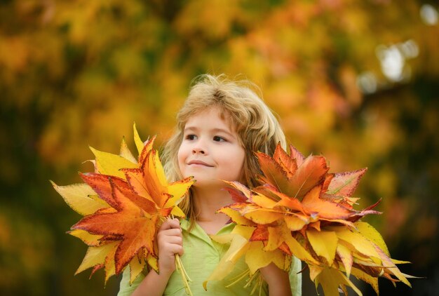 Herbstkinderstimmungskind mit Fallblättern über Ahornblatthintergrund