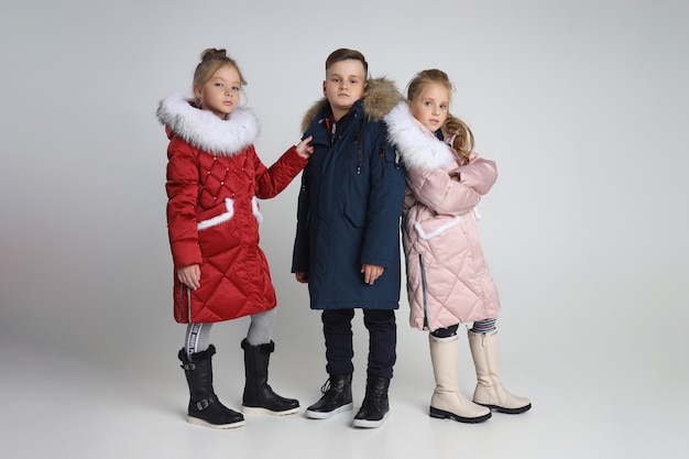Foto herbstkollektion von kleidern für kinder und jugendliche. jacken und mäntel für herbstkaltes wetter. kinder posieren auf einem weißen hintergrund
