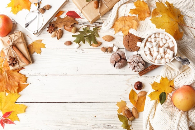 Foto herbstkomposition dunkler schal eine tasse kakao mit marshmallows herbsttrockene blätter auf einem weißen holztisch draufsicht kopierbereich