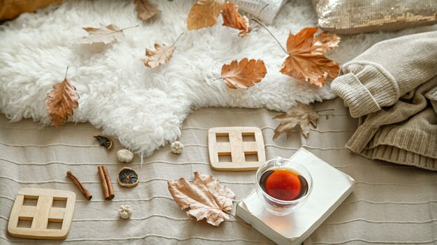 Herbstkomposition mit einer Tasse Tee, einem Buch und Details der Herbstdekoration.