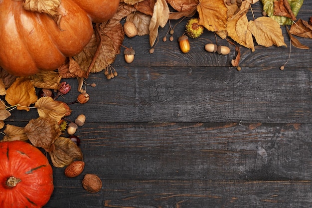 Herbstkomposition mit trockenen Blättern und reifen Kürbissen auf einem dunklen Holztisch Draufsicht Kopierbereich