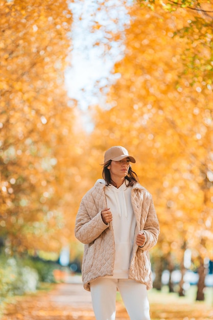 Herbstkonzept schöne Frau trinkt Kaffee im Herbstpark unter Herbstlaub