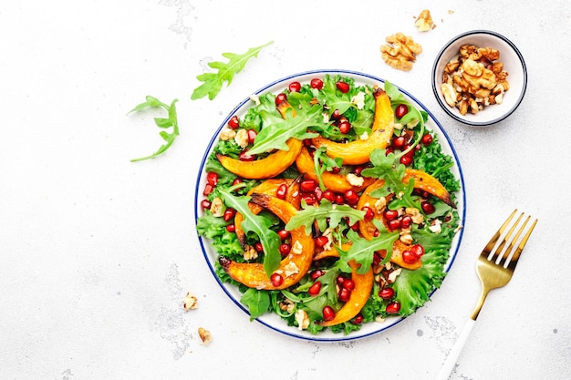 Herbstkürbissalat mit gebackenen Honigkürbisscheiben, Salat, Rucola, Granatapfelkernen und Walnüssen Gesunde vegane Ernährung Komfortnahrung Draufsicht