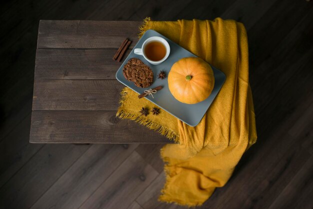 Herbstkürbisse und eine Decke auf einem Holztisch