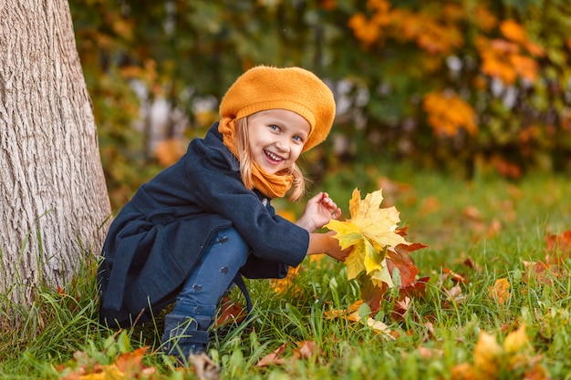 Herbstlächelndes Mädchen mit Ahornblättern im Herbstpark