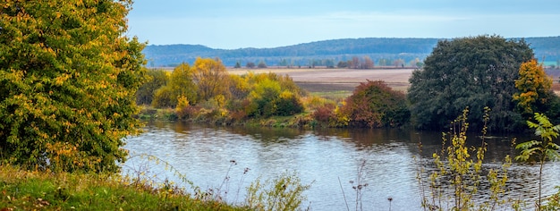 Herbstlandschaft. Bunte Bäume am Fluss im Herbst an einem sonnigen Tag