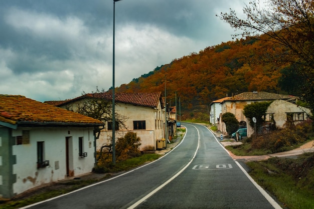 Herbstlandschaft, in der sich in der Mitte eine Straße und an den Seiten ein Haus und Vegetation befindet