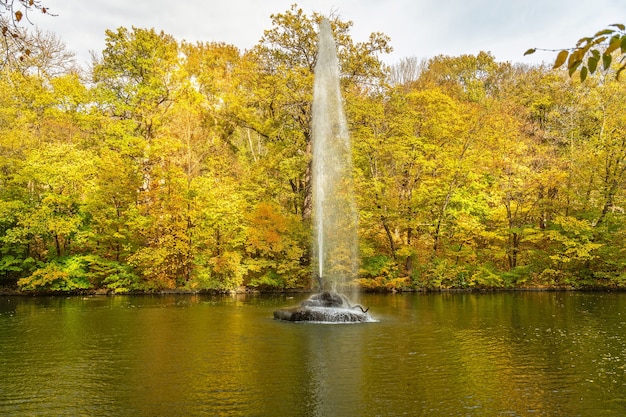 Herbstlandschaft mit Brunnen und gelben Bäumen