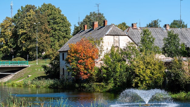 Herbstlandschaft mit historischem Mühlengebäude am Fluss und Brunnen Dobele Lettland