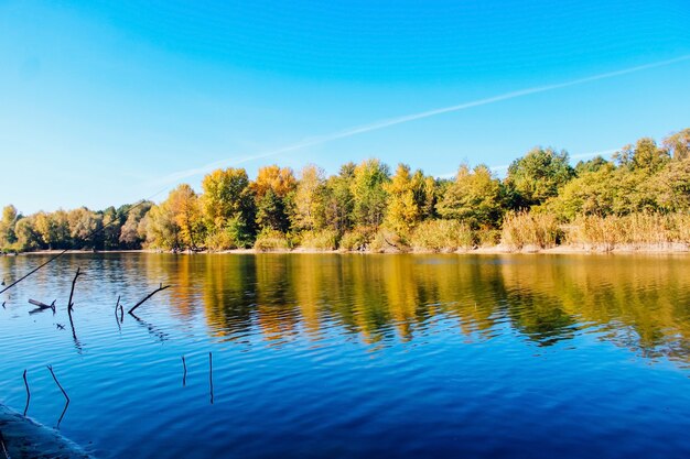 Herbstlandschaft über dem Fluss. Spiegelung gelber Bäume im Wasser