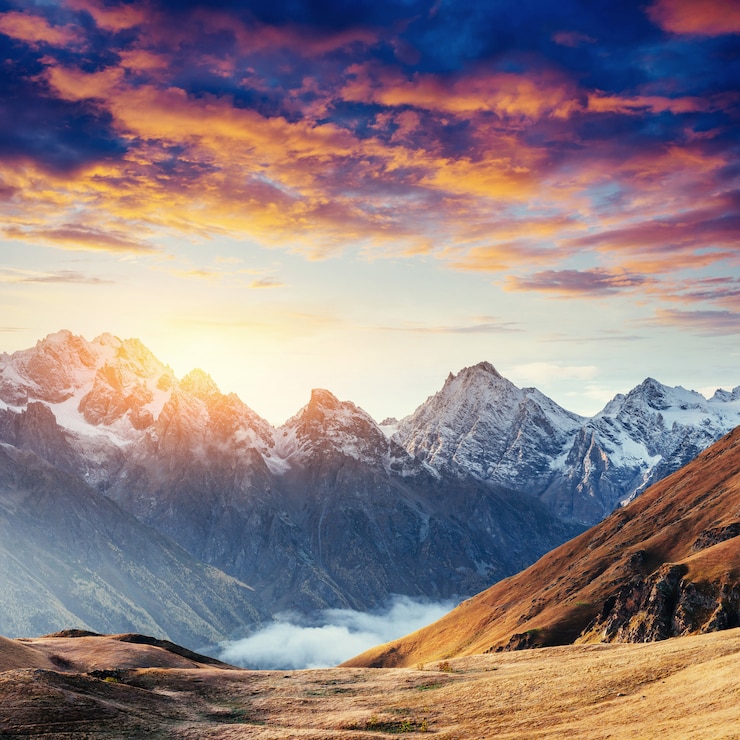 Foto herbstlandschaft und schneebedeckte berggipfel. fantastischer sonnenuntergang