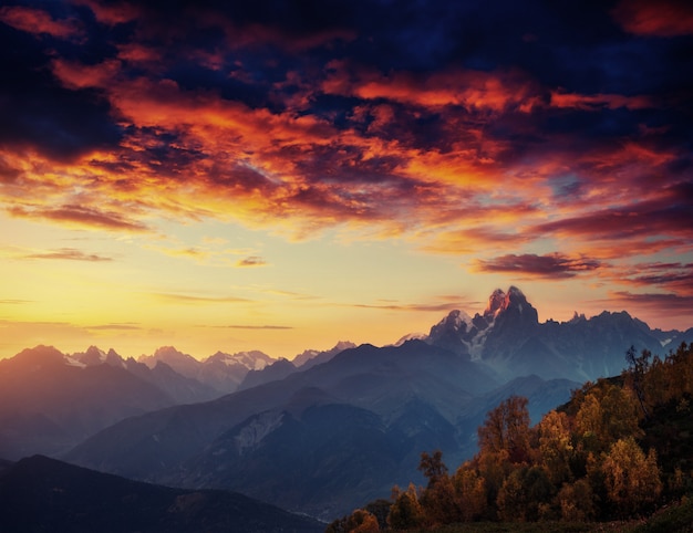 Herbstlandschaft und schneebedeckte Berggipfel. Fantastischer Sonnenuntergang