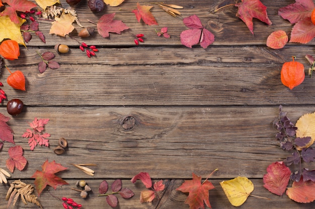 Herbstlaub auf darrk alter Holzoberfläche