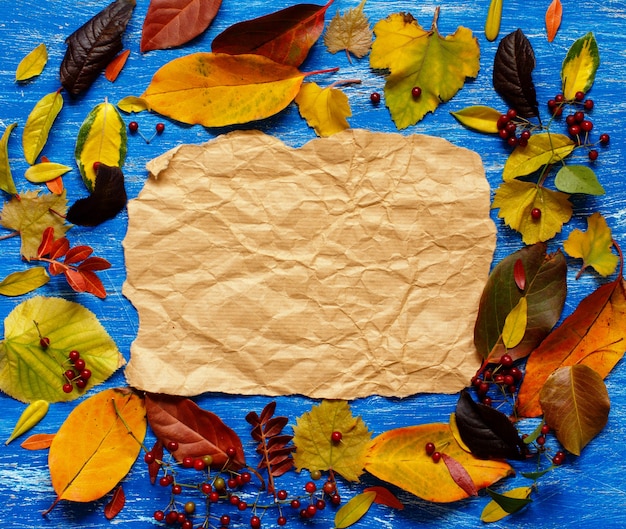 Herbstlaub und Papier auf blauem Hintergrund