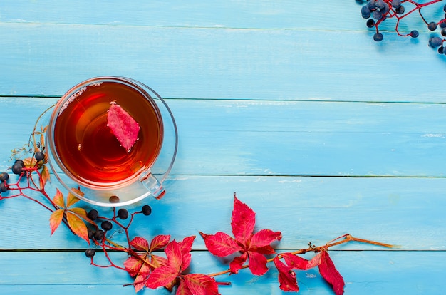 Herbstlaub und Tasse Tee auf Holztisch