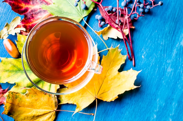 Herbstlaub und Tasse Tee auf Holztisch