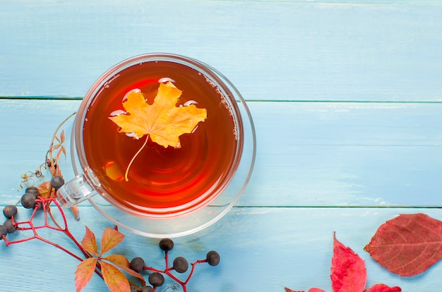 Herbstlaub und Tasse Tee auf Holztisch