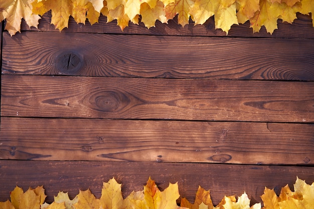 Herbstlaubrahmen auf hölzernem Hintergrund Draufsicht Fallgrenze gelb und orange Blätter Vintage Holztisch Kopieren Sie Platz für Text