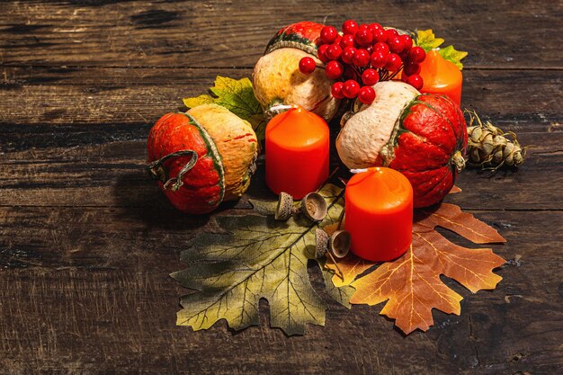 Herbstliche festliche Komposition auf altem Holzhintergrund. Dekorative Kürbisherbstblätter, Beeren, Eicheln