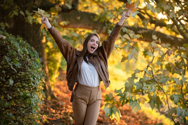 Herbstliche Frau mit herbstgelbem Ahornblatt im Freien, schönes Modell mit Herbstblättern