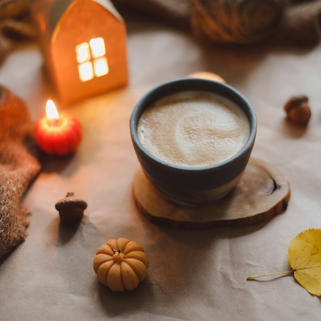 Herbstliche gemütliche Inneneinrichtung mit einer Tasse Kerzen karierten Hygge-Wohnkultur-Halloween- und Thanksgiving-Konzept