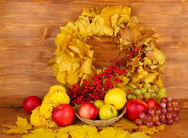 Herbstliche Komposition mit gelben Blättern, Äpfeln und Pilzen auf Holzhintergrund