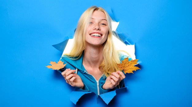 Herbstliche stimmung lächelnde frau mit ahornblättern, die durch papierlochrabattsaisonverkäufe schauen