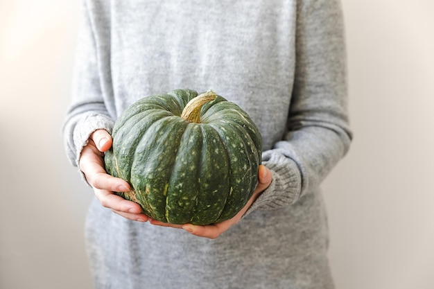 Herbstlicher Hintergrund, nicht wiederzuerkennende Frau, die Herbstkürbis in den Händen hält, isoliert auf weißem Rücken