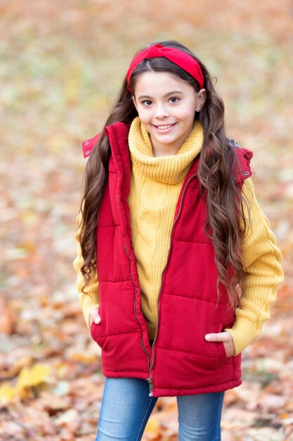 Herbstliches Mädchen lächelt im trendigen Herbststil im Freien. Fröhlicher Teenager im stilvollen Herbstoutfit an einem Herbsttag. Herbstmode für Teenager