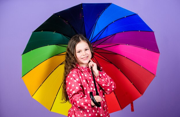 Herbstmode. kleines Mädchen im Regenmantel. Regenschutz. Regenbogen. fröhliches Hipster-Kind in positiver Stimmung. glückliches kleines Mädchen mit buntem Regenschirm. In ihrem eigenen Stil. Das Leben ist großartig.