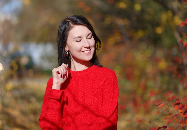 Herbstporträt einer jungen attraktiven brünetten Mädchenfrau in einem roten Pullover