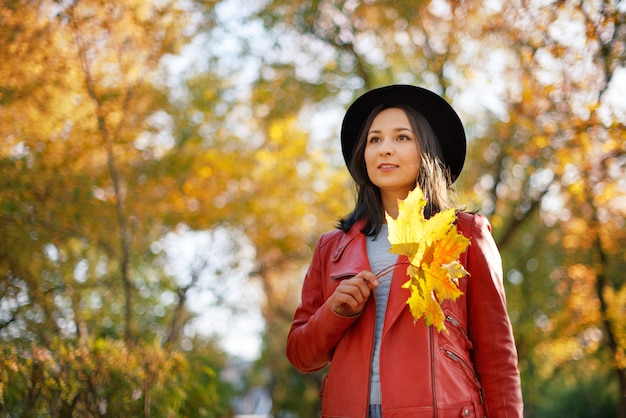 Herbstporträt einer Mädchenfrau in einem Hut und einer roten Jacke