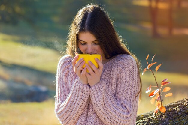 Herbstporträt eines Mädchens mit einer gelben Tasse