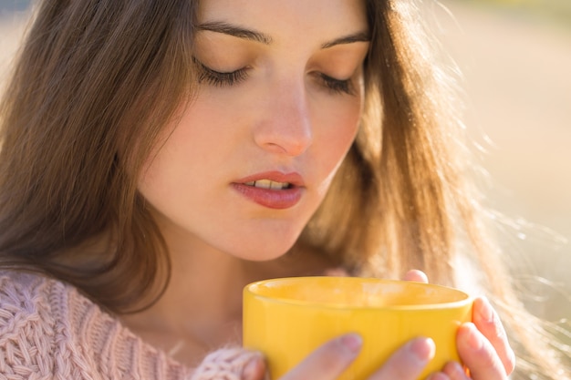 Herbstporträt eines Mädchens mit einer gelben Tasse