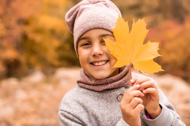 Herbstporträt im Freien eines schönen glücklichen Kindermädchens, das im Park oder Wald spazieren geht