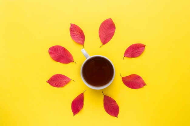 Herbstrotblätter und ein Tasse Kaffee auf einem hellen gelben Hintergrund